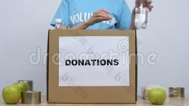 <strong>青年志愿者</strong>将罐装食品放入捐赠箱中，工作社会中心